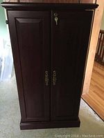 Front view of closed cabinet showing two-panel doors and brass hardware