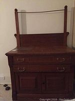 Front view of antique wooden wash stand with two drawers and two doors, showing dark wood finish and brass drawer pulls.