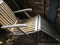Side view of folding wooden chaise lounge chair showing slatted seat, adjustable back and footrest with brass hardware