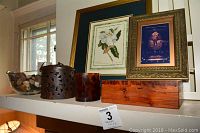 Shelf display showing framed magnolia print, King Tut print, two faux candles, wooden box, and glass bowl with river stones