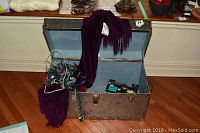 Open metal trunk displaying purple chenille throw draped over the edge, string lights inside trunk, and additional items.