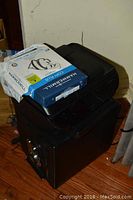 Overall view of the printer stacked on top of the black security safe, with the ream of paper visible.
