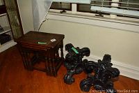 Photo of two black ornately carved pedestals and two wooden nesting tables stacked adjacent to a window