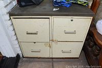Front view of a vintage double metal file cabinet with four drawers showing rust, chipped paint, and wear marks.
