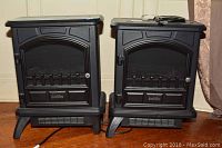 Two black Duraflame space heaters model DFI 500 side by side on wooden floor, showing full front and side profile.