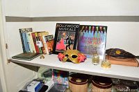 Lot overview showing books on shelves plus Venetian mask and perfume bottles on display surface