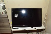 Front view of Samsung 24 inch LED HD TV on a white shelf with cables attached.