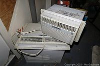 Three stacked Frigidaire window air conditioners showing size differences and attached cords.