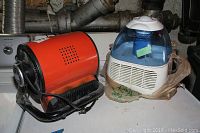 Photo of Black and Decker BDH105 heater and Vicks vaporizer on a surface near a washer/dryer and pipes.