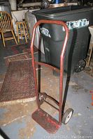 Red metal hand truck upright showing frame and handle.