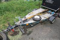 Side and front view showing trailer frame, tongue hitch, deck, axle and wheel