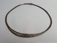 Sterling silver necklace laid flat showing tapered woven design with clasp visible