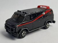 Front and right side view of die cast A-Team van toy showing black paint with red stripe and roof spoiler.