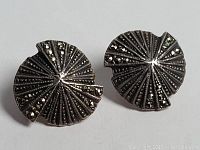Pair of sterling silver earrings shaped like Asian folding fans with fine linear detailing and marcasite stone decoration shown from an angle to highlight texture and metallic shine.