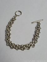 Clear image showing vintage sterling silver bracelet with double chain links and toggle clasp laid flat on white background.