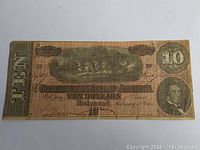 Front side image of the 1864 Confederate States of America ten dollar paper note showing central battle scene, portrait, and denomination.