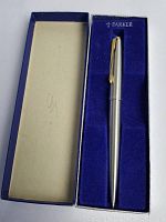 Open box displaying the silver-tone Parker pen with gold clip inside a blue velvet-lined container.