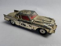 Side view of die cast model car showing gold paint wear and red interior windows.