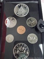 Coins arranged in black presentation case showing 1876-1976 double silver dollar, quarter, dime, nickel, and penny coins.