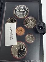 Complete coin set sealed in protective display showing various coins including silver dollars, 25 cents, and other denominations along with an inspection label.
