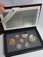 Coins displayed in black foam insert inside presentation box, showing silver double dollar Iron-Workers coin and six other Canadian coins.