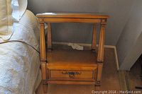 Front angle view of wood night stand showing drawer, carved legs and open shelf.