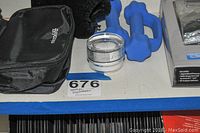 Medical equipment and accessories including blood pressure cuff, cream, weights, and Omron monitor box, arranged on a shelf with lot number tape.