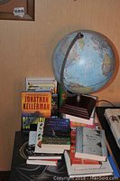 Overview photo showing the globe on a wooden base and multiple books stacked and arranged around it.