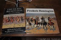 Two Frederic Remington coffee table books placed on a desk, showing the front cover of each.