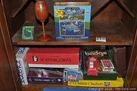 Shelf with various boxed board games and puzzle, including Scattergories, Sequence, Chinese Checkers, Bridge playing cards, and Lake Tahoe 500-piece puzzle