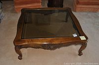 Full view of the square Henredon coffee table showing glass top and carved wood frame.