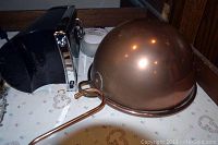 Photo showing black and chrome OneTouch automatic can opener and copper-colored dome roasting pan with long handle