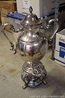 Antique silver samovar shown from front with handles and spigot visible