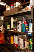 Front view of steel shelving showing paint cans, cleaning products, and chemicals on three shelves