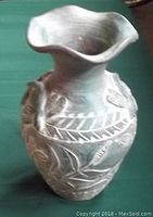 Front and angled view of a large hand-painted Mexican ceramic vase showing floral and leaf relief patterns and ruffled wide rim with a small chip.