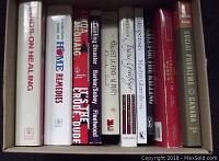 Ten hardcover and paperback books in a box viewed from the top showing titles on the spine.