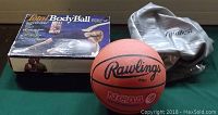 Photo showing the Total Body Ball box, a deflated BioBest exercise ball, and a Rawlings NCAA basketball on a green surface.