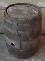 Straight view of the vintage wooden barrel showing the body, metal bands held by stainless steel wire, and the hole near the lower side.