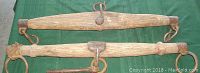 Vintage pair of single tree harnesses laid flat on a green background, showing full length and metal hooks attached.