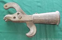 Side view showing overall shape, handle, and jaws of the fencing binder tool on a green background.