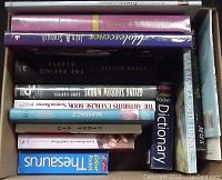 Top view showing assortment of books including dictionaries and novels stacked inside a box.