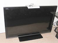 Front view of the Toshiba Regza 46 inch flat panel TV with black bezel and stand, remote control on top.