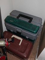 Image showing two fishing tackle boxes stacked together, one gray and green with black handle, the other brown with white handle