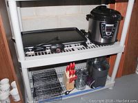 Top shelf of white plastic shelving unit showing Rival electric griddle and Power Cooker electric pressure cooker.