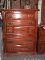Front view of the wooden dresser with visible brass handles and minor scratches.