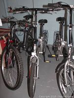 Side view of silver adult bicycle with visible fenders, rack, handlebars, and wheel details.