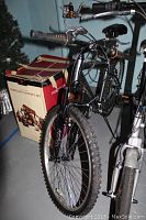 Front view of black Kolo men's mountain bike and part of other bike behind it, boxes in rear