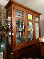 Front view of entire hutch showing glass display section filled with glassware.