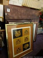Various framed artworks leaning against a wall including a multi-tiger head print and large framed print with ornate frame.