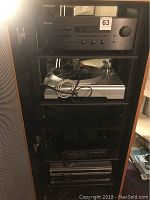 Full cabinet view showing six stacked components: Nakamichi receiver at top, ION turntable, Optimus receiver/cassette deck, Sony DVD player, Toshiba HD DVD player, LaserDisc player at bottom.